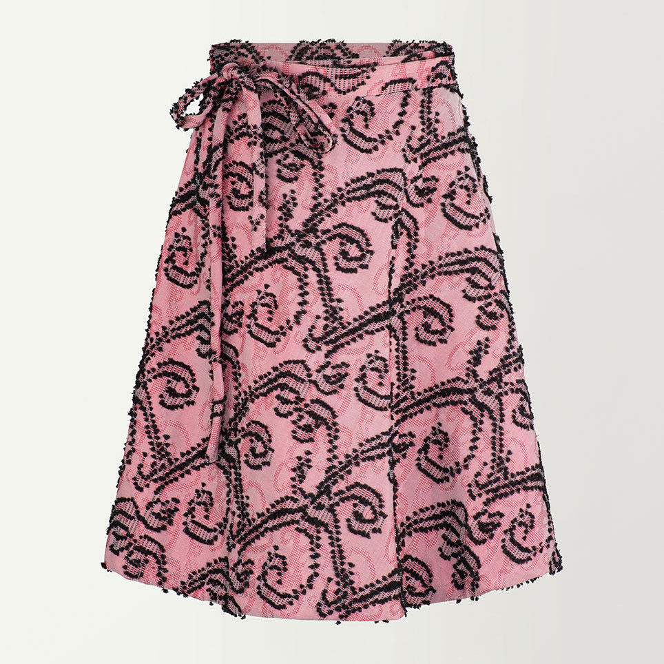 A pink A-line wrap skirt with a geometric pattern, tied around the waist.