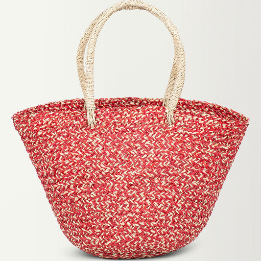A woven straw grass handbag with a red and black pattern and two handles.