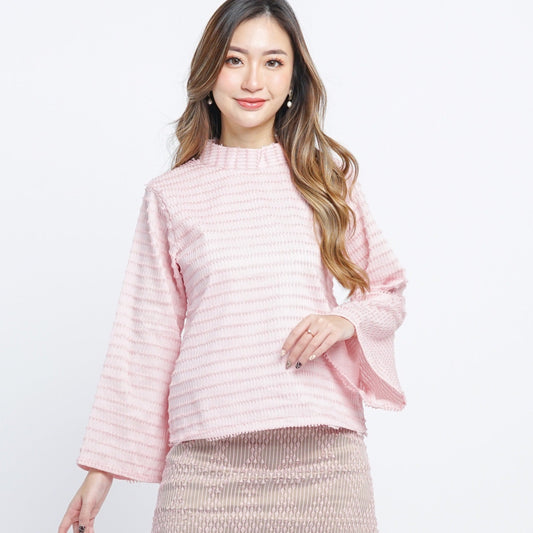 A woman wearing a traditional beige blush long sleeves top with a high neck, made with handwoven tenun fabric.