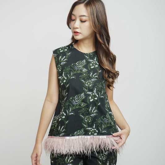 A sleeveless top with a floral batik pattern and a dramatic blush ostrich feather at the hem. The model is a woman with long hair and the photo is in black and white.